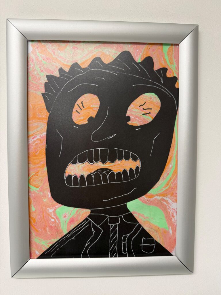 Drawing with orange and green background with a face and shoulders coloured in black.